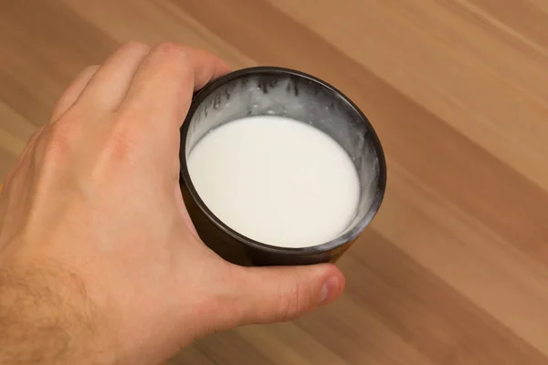 Taza negra con leche blanca sobre la mesa. Desayuno ligero en casa. — Foto de Stock