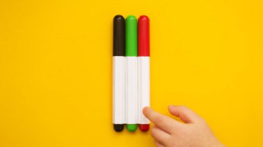 Masada üç tane renkli işaret var. Childs 'ın eli kalemi alıyor. Okula hazırlanıyorum. Bir çocuğa resim yapmayı öğretmek.