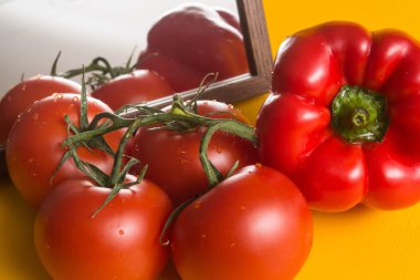 Aynanın yanındaki sarı masada kırmızı olgun domatesler. Mutfağa sebze ve yiyecek seriyorum. Kırmızı biber yansıtılır