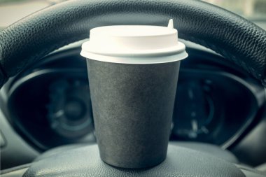 Direksiyonda duran mukavva bir kahve fincanı. Yolda dinlenme tesisi var. Arabada bir şeyler atıştır..