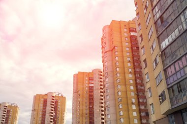 Evlerin dramatik kırmızı manzarası. Önünde sokak fenerleri, akşamında gökyüzü, güneş ışığı ve uzak dönen bulutlar.