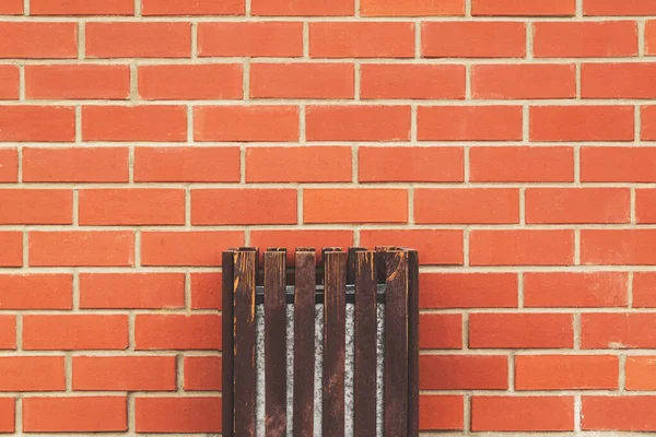 Wooden trash bin on a brick wall background.