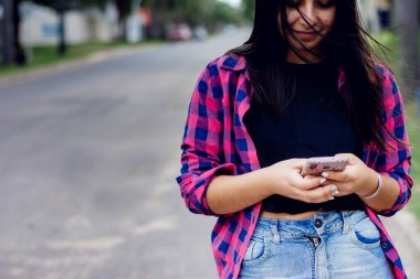 Şehirdeki telefonda mesaj okuyan genç bir kadın.
