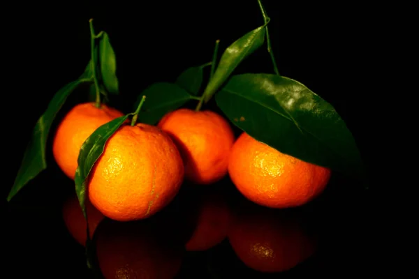 Tiga Mandarin Dengan Daun Terisolasi Pada Warna Hitam Dengan Refleksi — Stok Foto