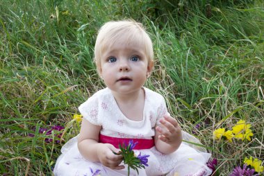 Parktaki çimlerin üzerinde oturan küçük kız