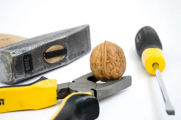 toughie clamped with pliers against a background of a hammer and