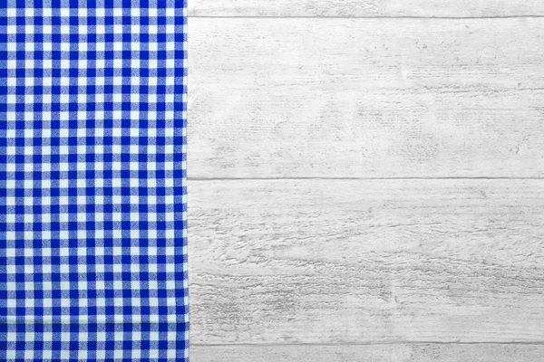 Blauw geblokte tafelkleed met een houten achtergrond — Stockfoto