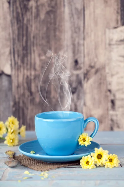 Taza de café azul humeante con flores amarillas — Foto de Stock