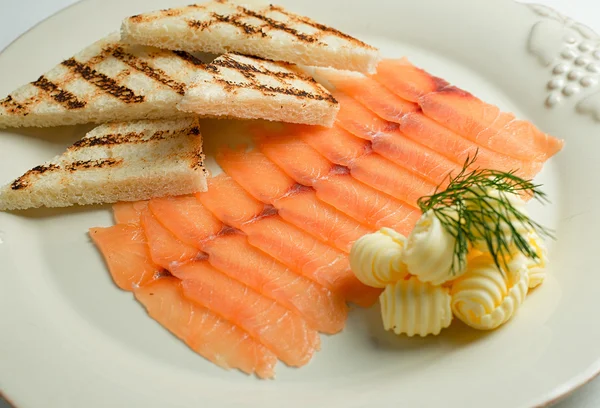 smoked salmon with toasts on white plate