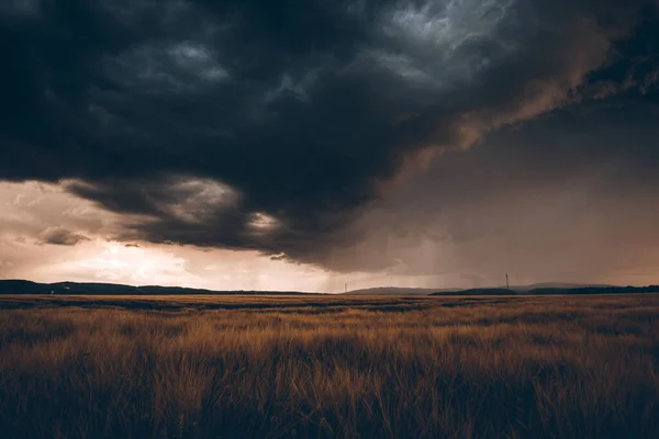 Yazın kır arazisi, kara fırtınalı bulutlarla dolu.