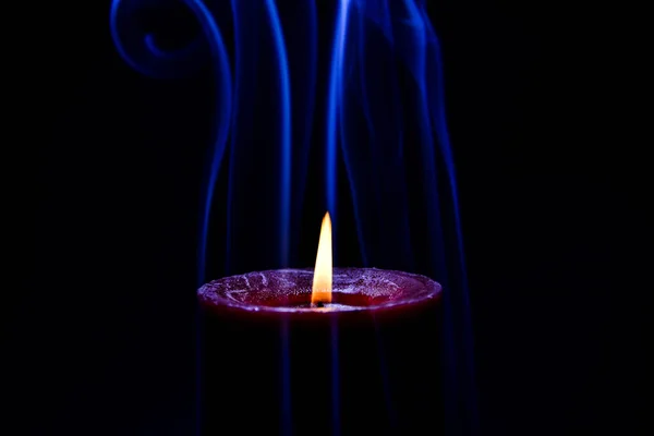 Red burning candle with blue coloured smoke