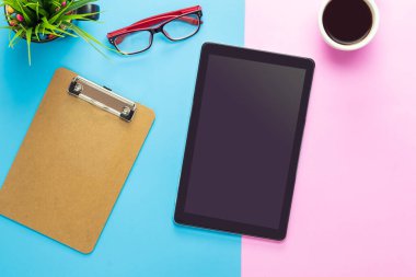 Ofis masası bilgisayar tableti, akıllı telefon pastel ton rengi, kopyalama alanı ve malzemeler. Kopyalama alanı olan üst görünüm