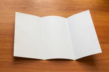 Beyaz modelleme, ahşap arka planda üç katlı broşür işi açtı.