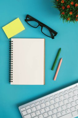 Üst görünüm çalışma alanı ofis işi masaüstü boş not defteri mavi arka planda ofis aksesuarları fincan kahve