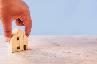 Erkek el ele tutuşan ahşap modeller, yatırım sigortası ve ev alımı, gayrimenkul konsepti