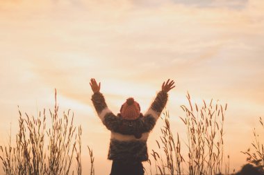 Genç bir kadın elleri yukarıda duruyor.