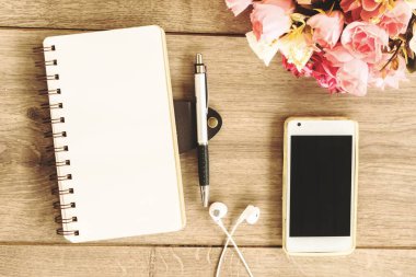Defter, akıllı telefon, kulaklık ve tahta arka plandaki kalem üst görünümü