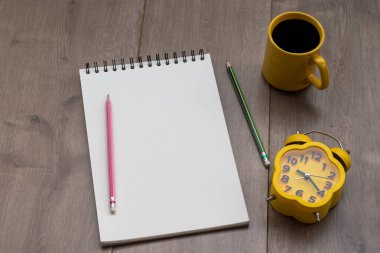 Boş defter, kalem, bir fincan kahve ve gözlüklü düz bir ofis masası. Kopyalama alanı olan üst görünüm