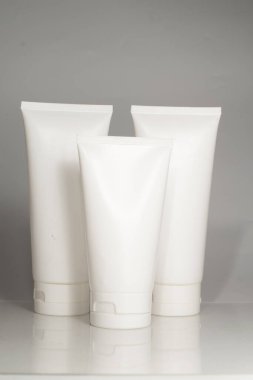 Gri arka planda beyaz kozmetik krem veya kozmetik ürünleri için losyon ambalajı.