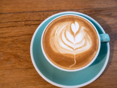 cappuccino bardağı ve masada sanat eseri.