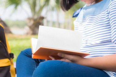 Kız parkta kitap okuyor.