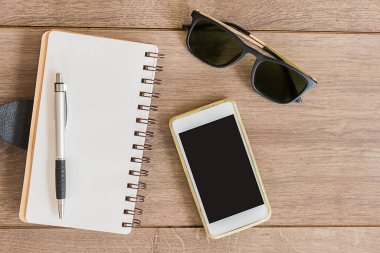 defter kağıdı ve cep telefonu ahşap masanın üstünde, üst görünümde.