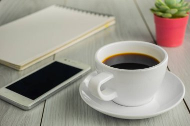 Kahve fincanını akıllı telefon ve defterle kapat.