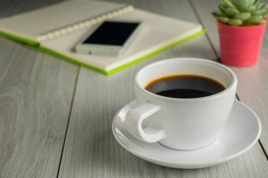 Kahve fincanını akıllı telefon ve defterle kapat.