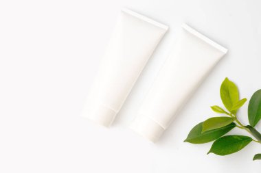 Yeşil zemin üzerinde boş yaprak olan beyaz kozmetik şişeleri.