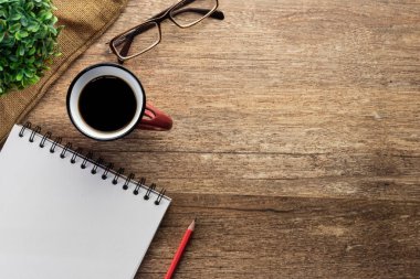 Ofis masası, akıllı telefon, kalem, bir fincan kahve ve gözlük. Kopyalama alanı olan üst görünüm