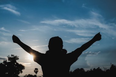 Siluet kadın ellerini günbatımı arka planına uzattı