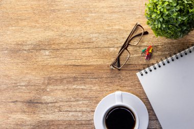 Ofis masası, akıllı telefon, kalem, bir fincan kahve ve gözlük. Kopyalama alanı olan üst görünüm