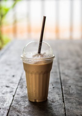 Krem şantili buzlu kahve eski ahşap masanın üzerinde plastik bardakta, üst veiw.