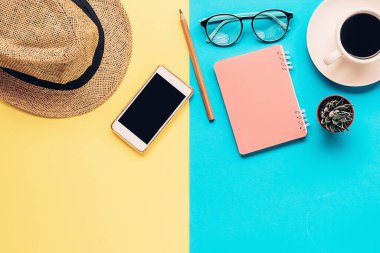 seyahat konsepti. Hasır şapka, akıllı telefon, defter, kalem, gözlük, kahve ve saksıdaki sulu çiçek manzarası 