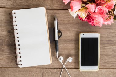 defter kağıdı ve cep telefonu ahşap masanın üstünde, üst görünümde.