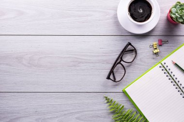 Ofis masası, akıllı telefon, kalem, bir fincan kahve ve gözlük. Kopyalama alanı olan üst görünüm