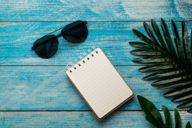 Mavi ahşap üzerinde yeşil yapraklı boş not defteri