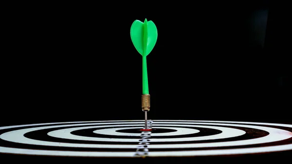 Siyah arkaplanda dart tahtasının ortasında kırmızı dart oku