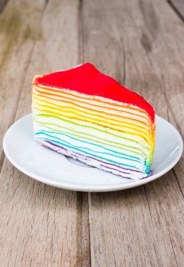 Ahşap masanın üzerinde katmanlı kek olan gökkuşağı pastası