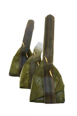 Beyaz arka planda muz yaprağına sarılı hindistan cevizi ile buğulanmış un.