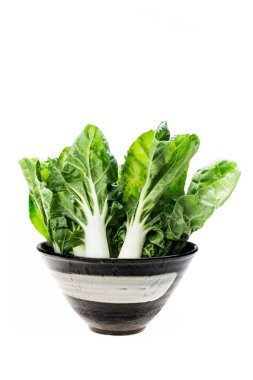 Tabakta bir sürü bok çuvalı, beyaz arka planda izole edilmiş. Asya yapraklı yeşil sebze.