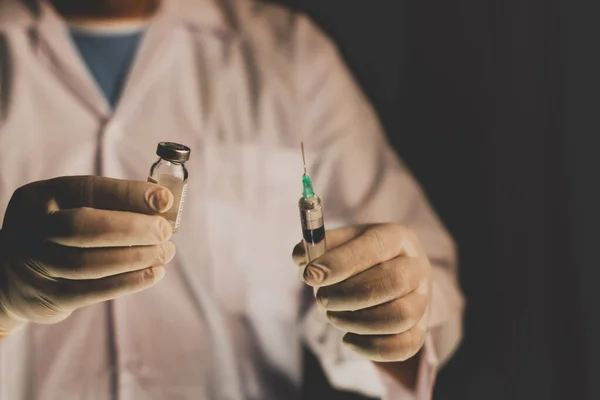 Doctor filling syringe from vial and hands with medication, closeup. Vaccination and immunization injection.selective focus,vintage color