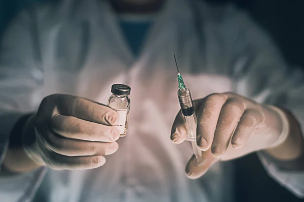 Doctor filling syringe from vial and hands with medication, closeup. Vaccination and immunization injection.selective focus,vintage color