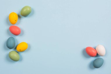 Paskalya arkaplanı, ahşap üzerinde el yapımı renkli yumurtalar parlak mavi bir arka plan. Çerçeve ve kopyala. 