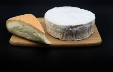 Chaumes ve Camembert peyniri kesme tahtasında. İki farklı izole edilmiş siyah arka planda yumuşak inek peyniri.