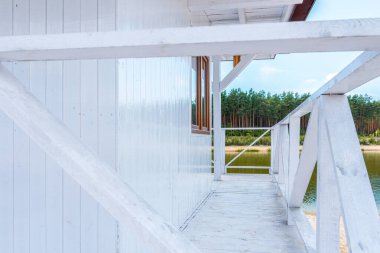 White, wooden lifeguard booth against lake and forest view (close-up)
