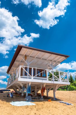 White, wooden lifeguard booth situated on sand beach against blue, cloudy sky