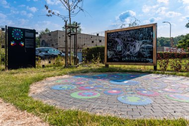 Büyük, ahşap tebeşir tahtası ve oyun parkının dışındaki renkli kaldırım oyunu. Güneşli bir gün, arka planda ağaçlar.