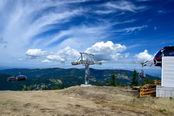 Modern chairlift station in the mountain resort Szczyrk, beautiful clouds and blue sky, ski infrastructure for transporting tourist and skiers
