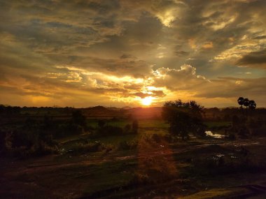Güneşli gün batımı altın gökyüzünde parıldıyor.